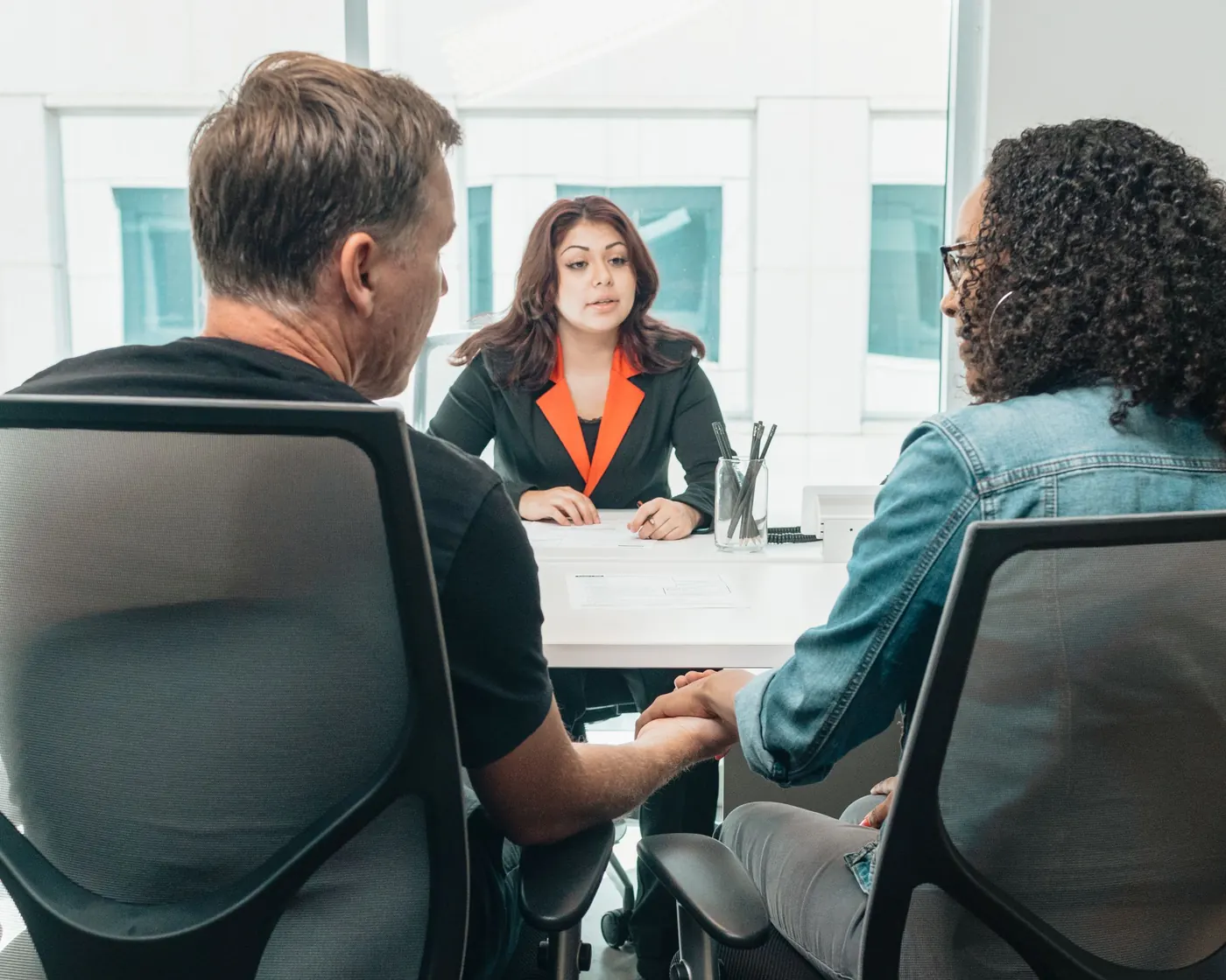 An adviser meeting two clients at her desk