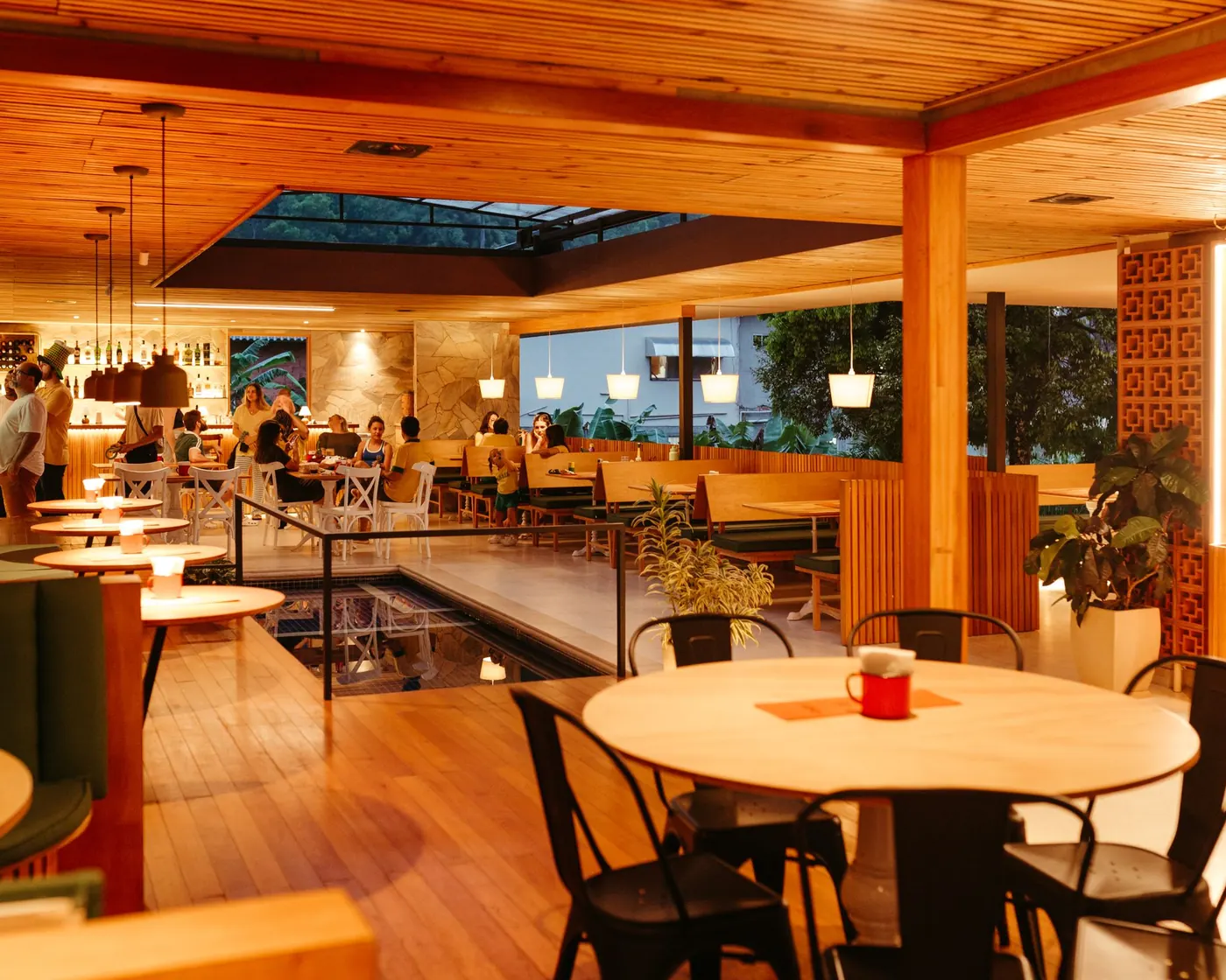A warm restaurant dining room with wooden tables and diners