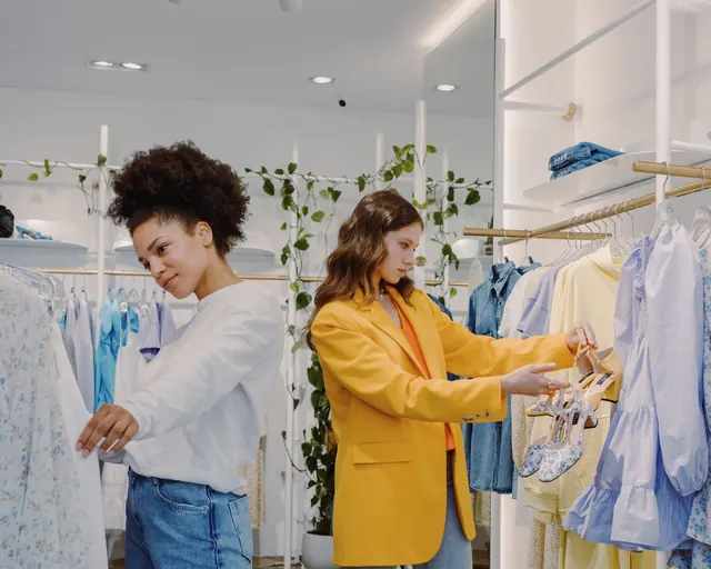 Two customers browsing clothes in a retail store